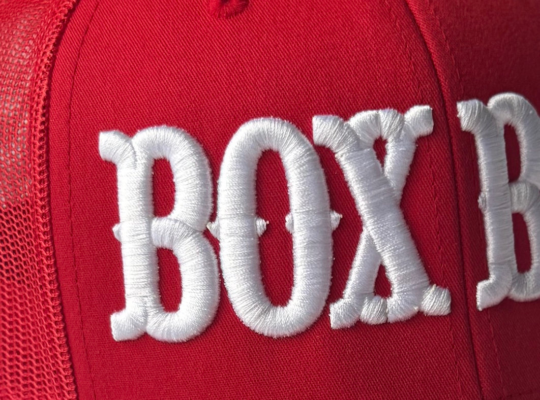 Close-up of BOX BOX white 3D puff embroidery on red trucker hat