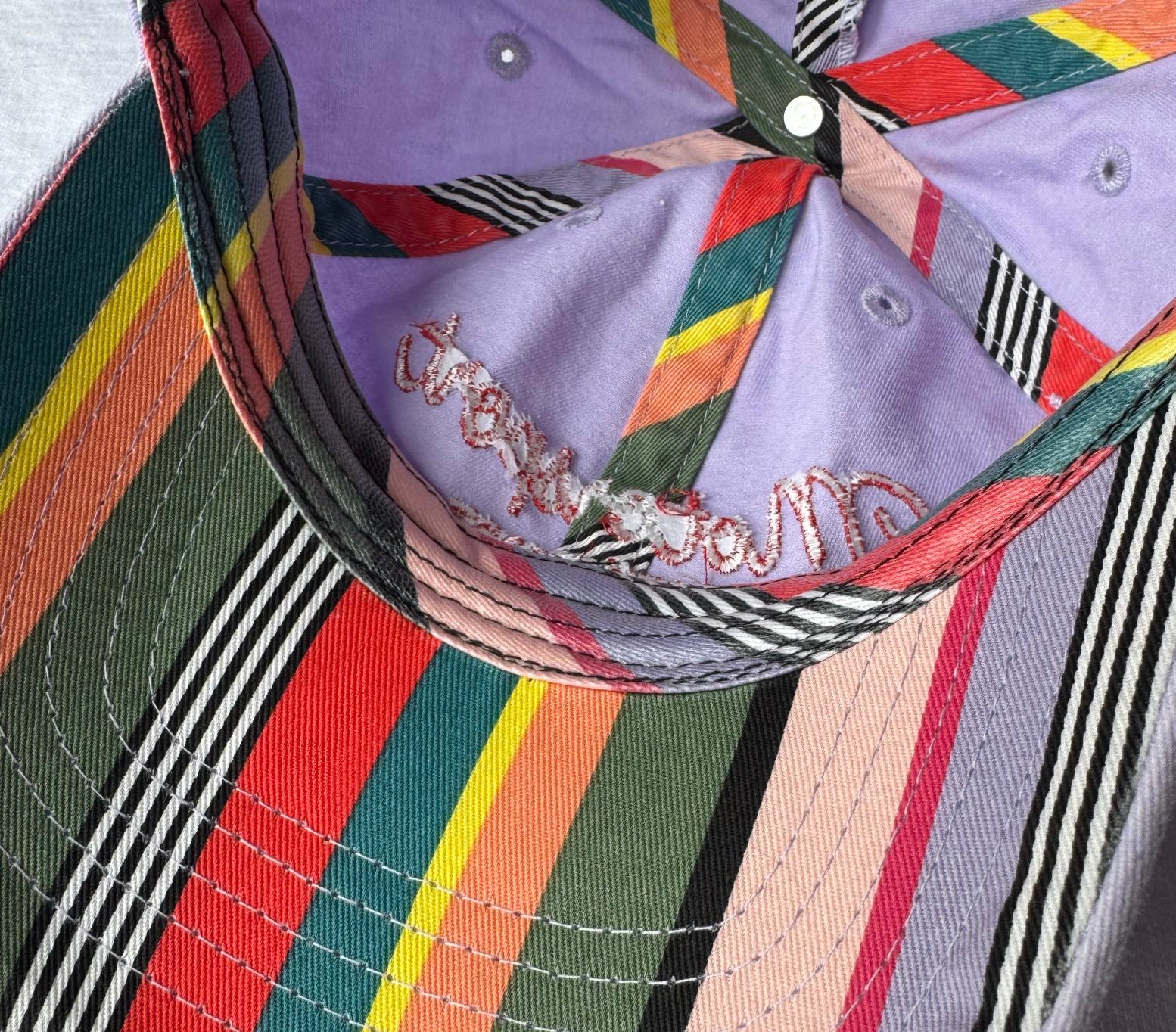 Close-up of striped undervisor and interior taping on Chassey lavender Motorsport Enthusiast cap