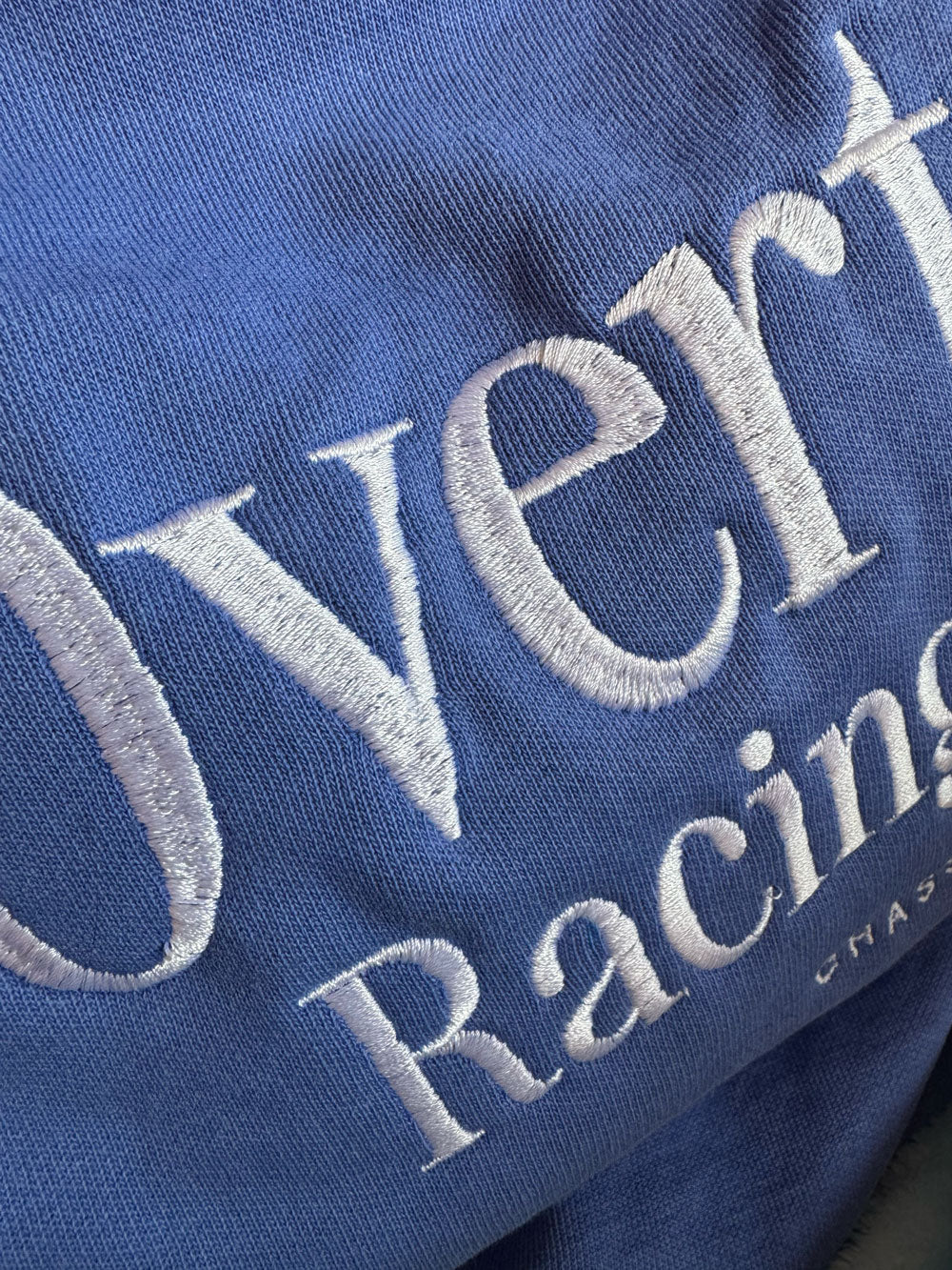 Close-up of Overtake Racing Dept embroidery on flo blue Chassey crewneck