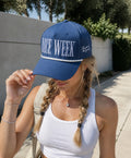Woman wearing a blue cap with 'Race Week' text outdoors